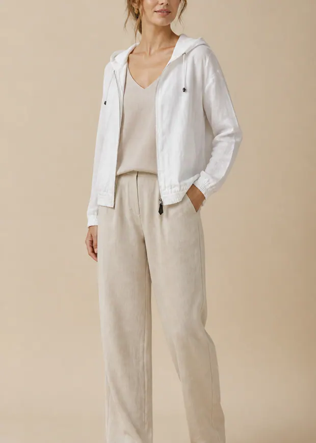 Woman wearing a white linen-blend hooded jacket with beige trousers