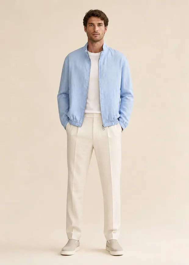 Man wearing a shell-blue bomber jacket with white trousers